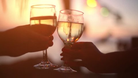 Couple is toasting with wine glasses during a beautiful sunset with bokeh lights. 1920x1080