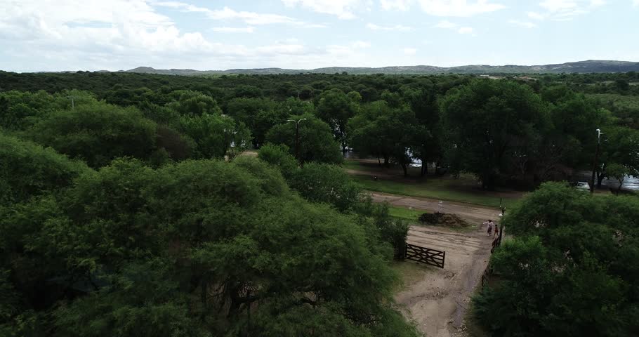 Aerial drone scene of brown strong river passing over bridge. Flood in Mina clavero. Growing river over city streets. Ascending and flying towards and over water. Cordoba, Argentina