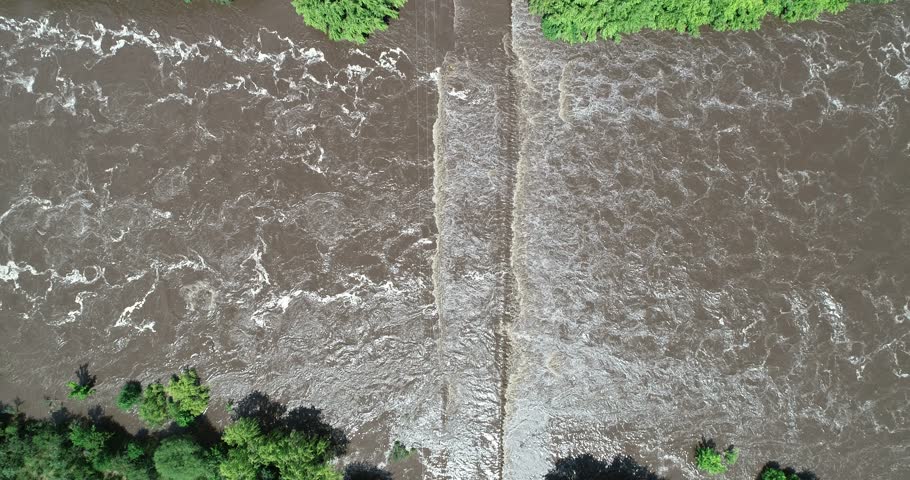 Senital aerial scene of flooded bridge, brown muddy water passing over construction. General view of bridge and vegetated coast. Mina clavero, traslasierra, cordoba argentina