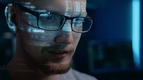Portrait of Software Developer Hacker wearing Glasses Working on Computer, Projected Code Numbers and Characters Reflect on His Face. Dark Room Full of Technology. Zoom in Shot - Powered by Shutterstock - Get 15% off with code: PIKWIZARD15