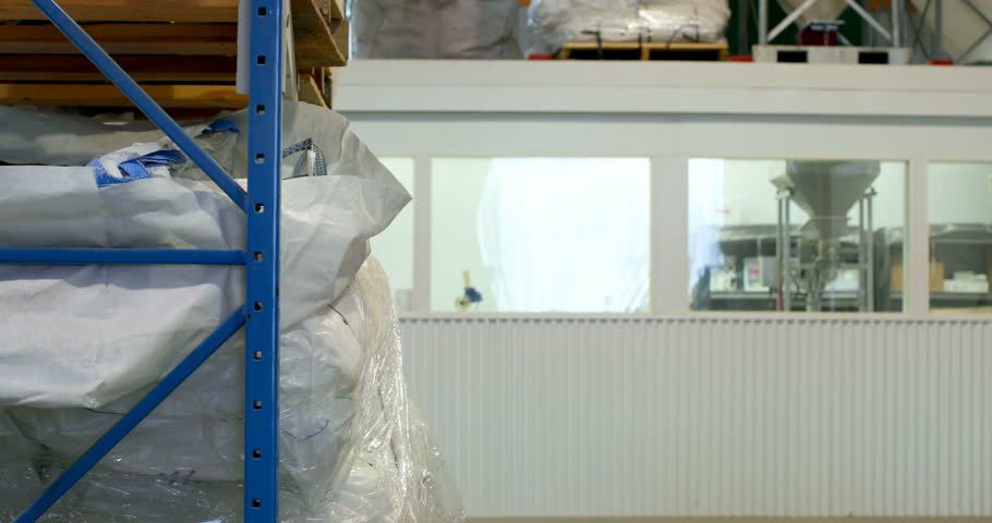 Side view of young caucasian female worker checking stock in factory. 4k