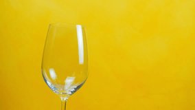 Red wine poured in a glass isolated on yellow - Video
