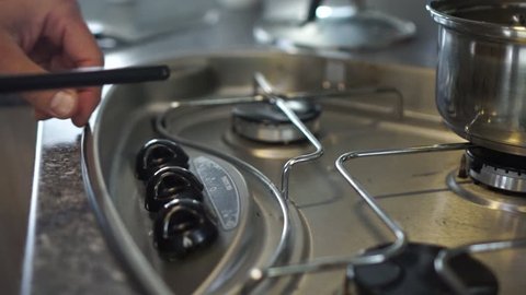 SLOWMO Close up - Lighting up gas stove burner fire and a pot of water in kitchen of motorhome