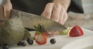 ?hef cuts strawberries in half with sharp knife. 4k slow motion video