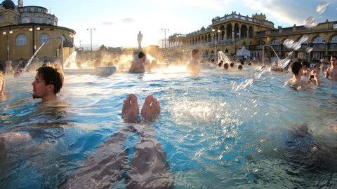 HUNGARY, BUDAPEST - FEB 21, 2018: A lot of people enjoy swimming in outdoor warm thermal pool in winter. Szechenyi medicinal bath is largest therapeutic swimming complex with thermal springs in Europe