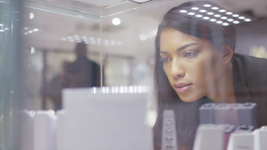 Young female seen looking at jewellery in a store, shot through glass Royalty-Free Stock Footage #1024766861
