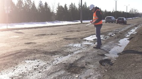 Inspector examines and checks holes in the road, bad road