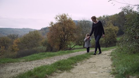 Mother with her young daughter walking along a path and looking out at the beautiful rural Tuscany landscape. Wide shot on 8k helium RED camera.