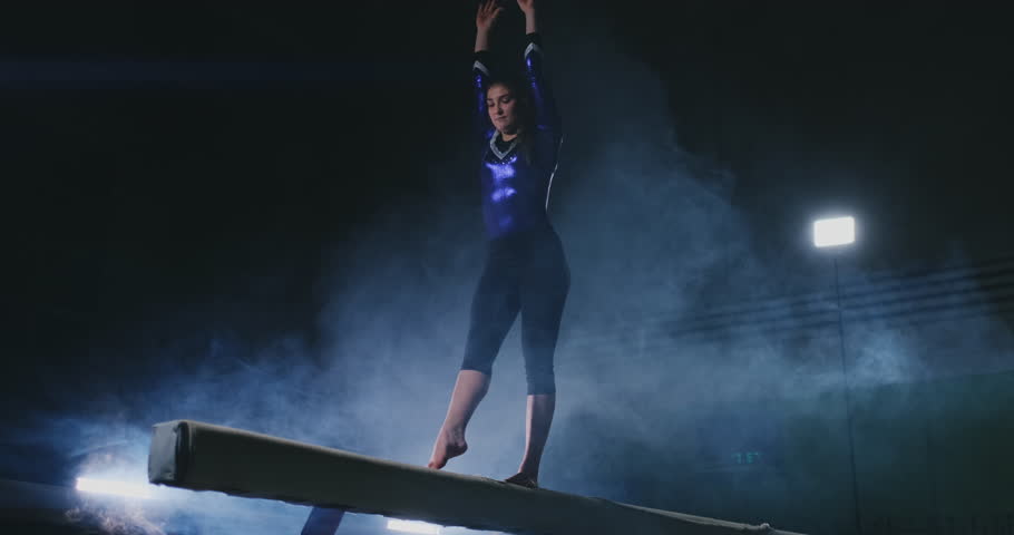 Legs Professional girl gymnasts jump in slow motion in the smoke on the balance beam. Women's Artistic Gymnastics Royalty-Free Stock Footage #1024774256