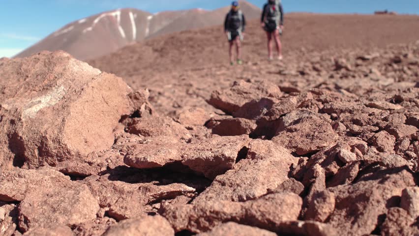 Low angle, soft focus shot of people running by the camera. Athletes jogging on stones.