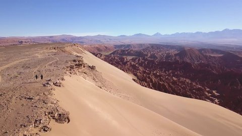 Epic fallowing aerial shot of people running in a dry desert, under extreme conditions.
