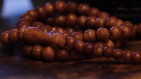 Muslim prayer beads on wooden table in low lights. Selective focus.