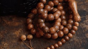 Muslim prayer beads on wooden table in low lights. Selective focus. Panning to the right.