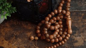 Muslim prayer beads on wooden table in low lights. Selective focus. Panning to the right.