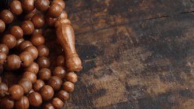 Muslim prayer beads on wooden table in low lights. Selective focus. Panning to the left.