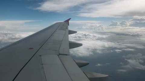 Flight of the plane on a flight level, against the background of blue sky and textural volumetric clouds. The view from the cockpit of the angle of view back, in the foreground a gray wing of an