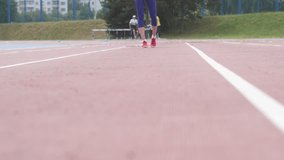 Young beautiful girl athlete training running fast start at the city athletics stadium during a day training in slow motion 4K video on UHD camera