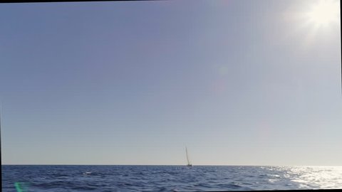 Fast paced panoramic shot over the Mediterranean Sea with sailboat floating and over the horizon.