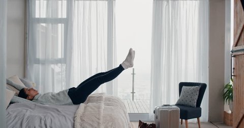 happy young woman jumping on bed resting after successful travel journey enjoying independent lifestyle freedom in hotel room