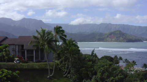 Hanalei Resort beautiful bay aerial 4k drone reveal view, Kauai North Shore, Hawaii. Shoreline, beach, palm trees and waves in tropical paradise 