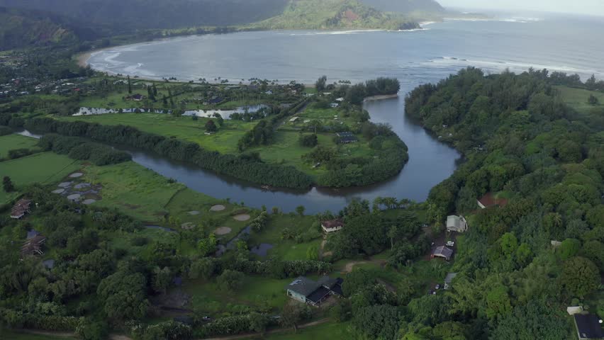 Hanalei river and bay in aerial 4k drone view, Kauai North Shore, Hawaii. Cliffs, coastline, beach, palm trees and waves in tropical paradise. Scenic sunrise light and ocean