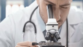 selective focus of male scientist looking through microscope in laboratory