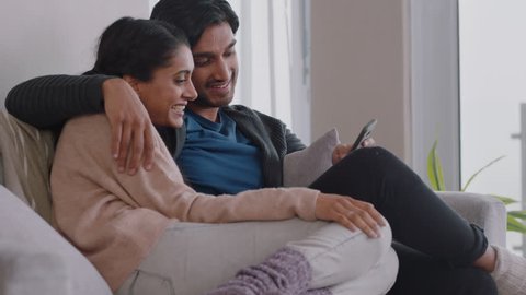 happy couple relaxing at home using smartphone together shopping online enjoying browsing internet relaxing on couch