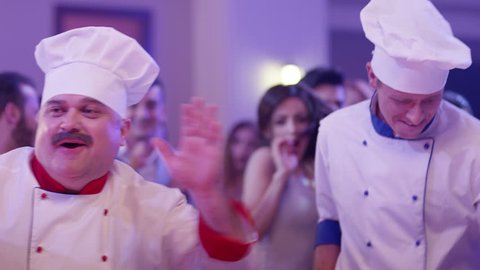 Cook dancers having fun dancing at a colorful party . Funny cook chef in white uniform, with a hat and ladle , smiling and partying during party . Shot on RED EPIC Cinema Camera .