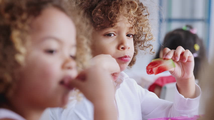 Close up of children eating their packed lunches together at infant school, rack focus Royalty-Free Stock Footage #1024820837