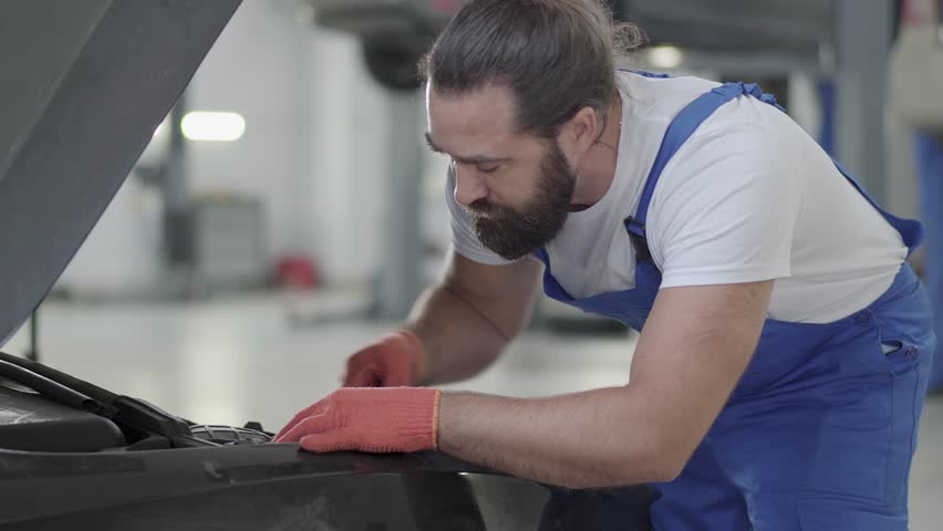 Proffesional car maintenance at service station. Car service, repair, maintenance and people concept - mechanic man working at workshop