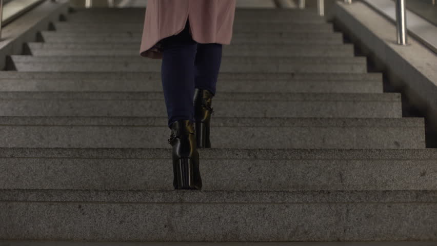 Female in fashionable shiny high-heel boots going upstairs, footwear quality