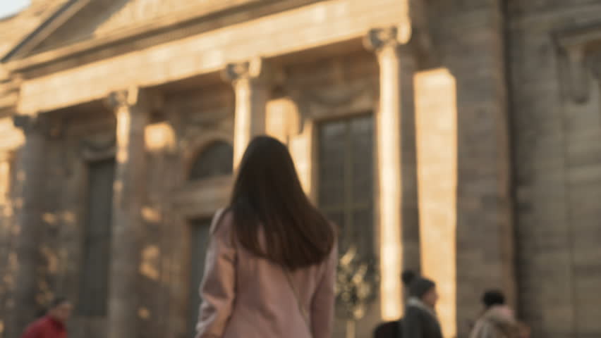 Attractive young woman turning to camera, standing near university campus