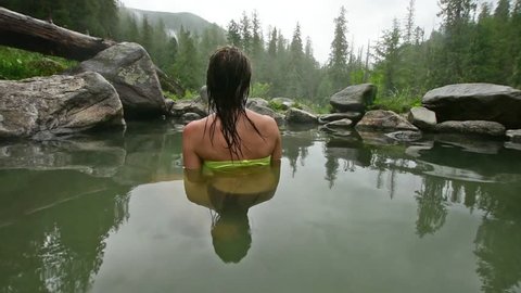 Woman looks out at misty forest while soaking in hot thermal pools in Idaho