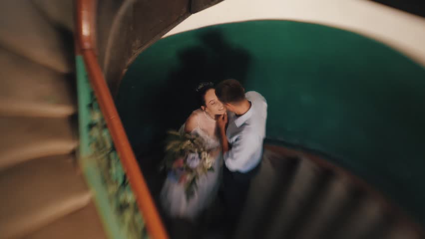 beautiful and young bride and groom go down the stairs