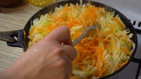 Sauerkraut in a frying pan. Stirring with a wooden spoon. The view from the top. Gas cooker. Fire. 4K video