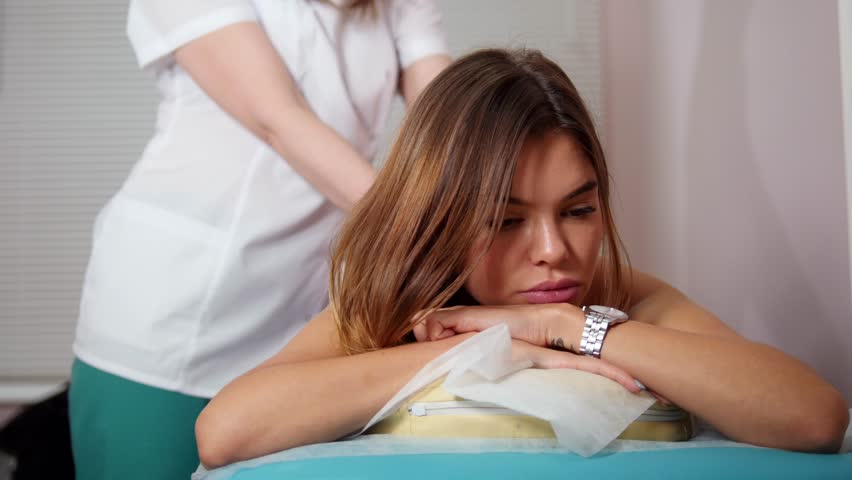 Massage procedure. Masseur giving a relaxing back massage to a young beautiful woman