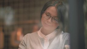 Close up of one Chinese women sit and read, short hair, wear glasses and spending leisure time indoor at cafe shop by the window, lifestyle of asian female learning and working 4k clip