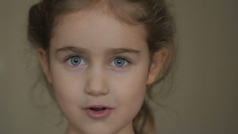Girl looks and is surprised and happy to receive a surprise. Portrait little girl with blue eyes looking at camera. Closeup. Portrait of young child surprised and shocked . Close up.