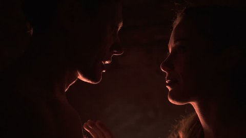 Heads silouettes of naked lovely couple in the darkness, boyfriend and girlfriend kissing and touching each other.