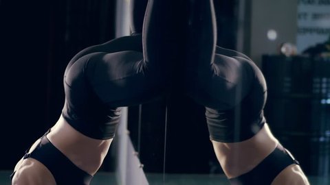 close-up, female ass, booty, hips, in black leggings, girl dancing twerk in the studio. beautiful figure, big booty woman on a black mirror background in dark. Fitness, crossfit, dancing, health