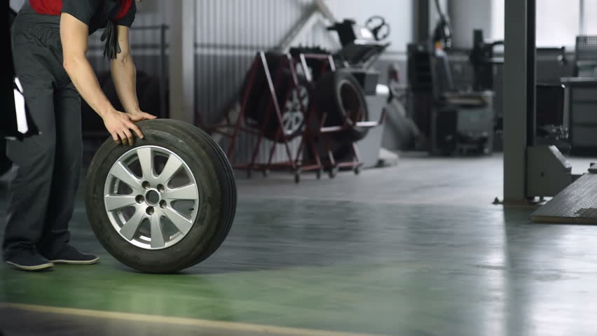 Mechanic holding a tire tire at the repair garage. replacement of winter and summer tires. Royalty-Free Stock Footage #1024861832