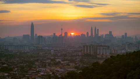 Timelapse of Kuala Lumpur city skyline cityscape starting at the sunset ending at night from afar with yolk sun in Federal Territory, Malaysia.