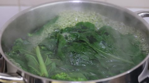 boiling green vegetables in water in iron pot