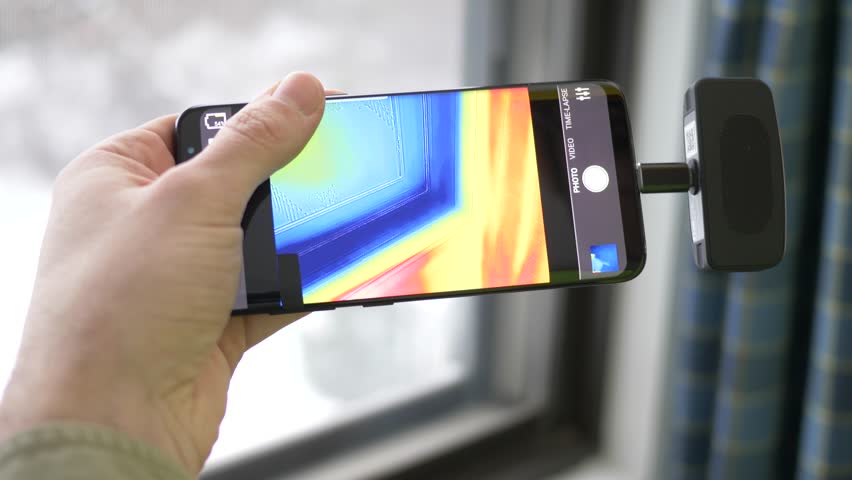 Worker inspecting using a thermal imaging camera connected to a smartphone. Trying to find water leaks, heat loss and take the temperature of objects. Thermography concept. | Shutterstock HD Video #1024869485