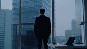 Back View of the Thoughtful Businessman wearing a Suit Standing in His Office, Contemplating Next Big Business Deal, Looking out of the Window. Business District Panoramic Window View - Powered by Shutterstock - Get 15% off with code: PIKWIZARD15