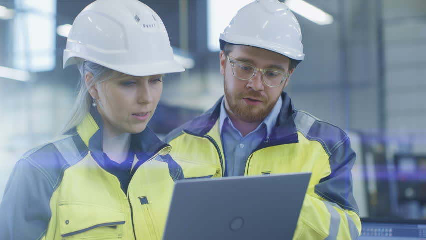 At the Factory: Male Mechanical Engineer Holds Component and Female Chief Engineer Work on Personal Computer, They Discuss Details of the 3D Engine Model Design for Robotic Arm. Royalty-Free Stock Footage #1024871570