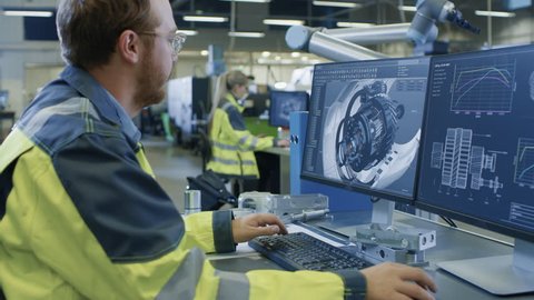 At the Factory: Male Mechanical Engineer and Female Chief Engineer Work on Personal Computers, They Design Details of the 3D Engine Model Design for Robotic Arm to Assemble.