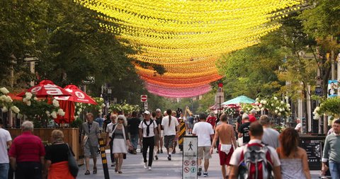 Montreal, Quebec, Canada - August 23, 2018: People walk along Saint Catherine Street in the gay village of Montreal Quebec Canada during Summer. Multi coloured balls hang in decoration overhead.