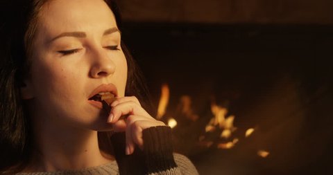Portrait of Woman Indulging in Eating Chocolate Bar Feeling Intimate at Fireplace shot on Red Camera
