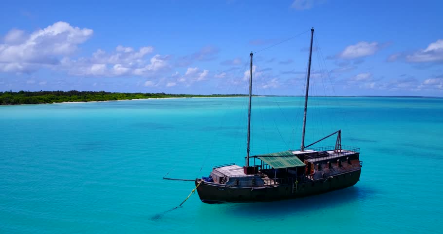 Wooden boat anchored in crystal clear turquoise waters in Maldives lagoon
